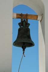 Obraz premium Closeup of a traditional church bell hanging from a wooden pilar and the aegean sea in the background in Santorini