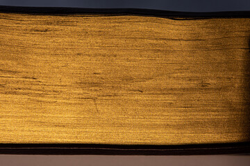 Close up of pages of a book with golden edges, golden texture background