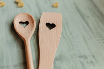 Liebe und Kochen - Kochlöffel aus Holz mit Herz auf mintgrünen Hintergrund 