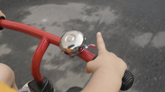 The child rides a bicycle while driving, rings a bell on the steering wheel.