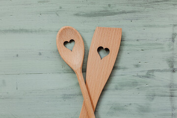 Liebe und Kochen - Kochlöffel aus Holz mit Herz auf mintgrünen Hintergrund 
