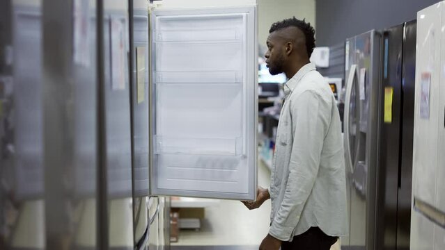A man inspect the design and quality of fridge before buying in a consumer electronics store