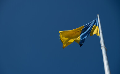 Flag of Ukraine flutters in blue sky. Large yellow blue Ukrainian national state flag. War