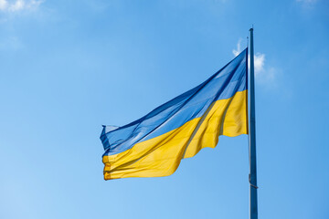 Flag of Ukraine flutters in blue sunny sky. Large yellow blue Ukrainian national state flag. War