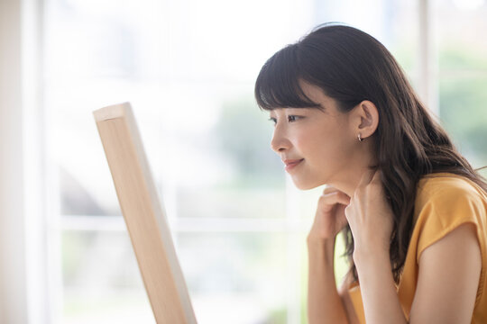 鏡を見ながらアクセサリーを身につける女性