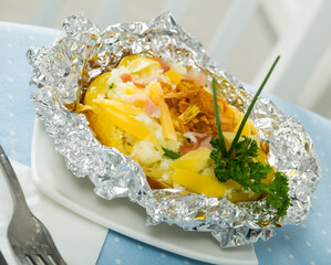 Delicious potatoes baked in foil with stuffing of grated cheese, bacon and greens..