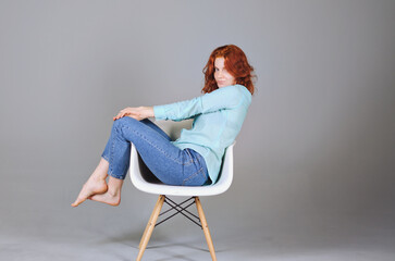 Business portrait of beautiful happy young woman with red curly hair and blue eyes against colorful, gray background. Lifestyle. 