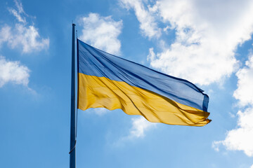 Flag of Ukraine flutters in blue sky. Large yellow blue Ukrainian national state flag. War