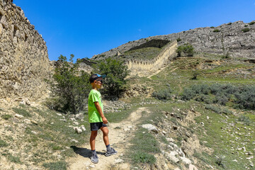 A boy against the background of the Gunib fortress. A protective wall. Russia, Dagestan. June 2021