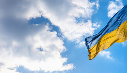Flag of Ukraine flutters in blue sky. Large yellow blue Ukrainian national state flag. War