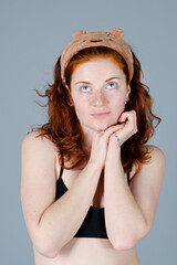 Business portrait of beautiful happy young woman with red curly hair and blue eyes against colorful, gray background. Lifestyle. 