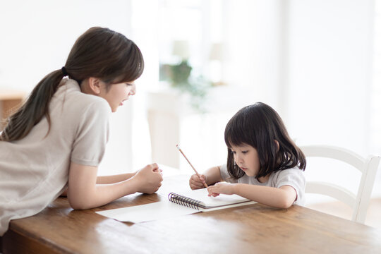 お絵描きする女の子と見守る母