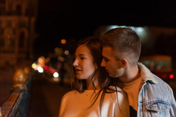 Beautiful young couple stands on the street at night. Romantic date.