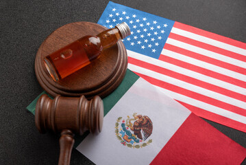 Bottle of whisky or other alcohol and judge gavel on flags of the United States and Mexico. Alcohol...