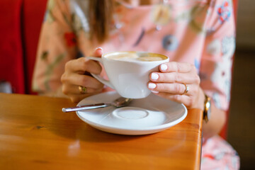 Female holding a cup of coffee in a cafe.
