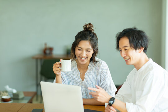 部屋でノートパソコンの画面を見る男女