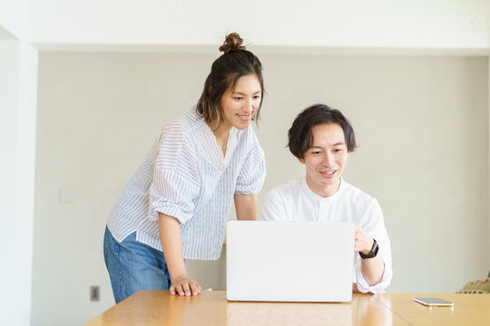 部屋でノートパソコンの画面を見る男女