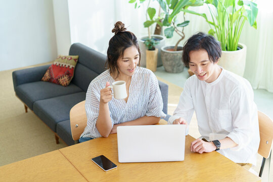 部屋でノートパソコンの画面を見る男女