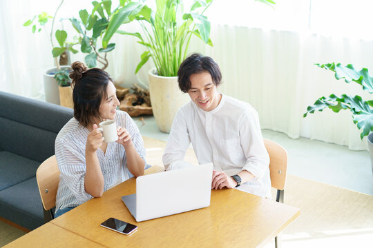 部屋でノートパソコンの画面を見る男女