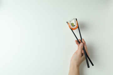 Female hand hold chopsticks with roll on white background