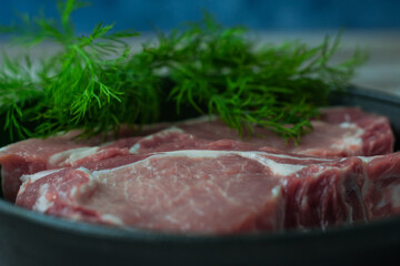 Close-up photo of cuts of meat with dill greens in a steak pan.