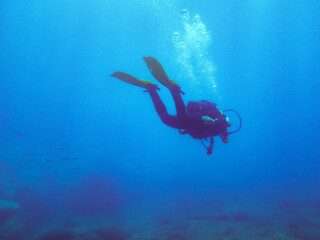 Buceador en el fondo y aguas azules profundas. Buzo expulsando el aire en forma de burbujas en Puerto Mogán, Gran Canaria, España.