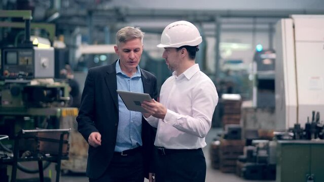 Two engineers at an industrial plant. Two workers control the work at the factory. Manufacture of cutting tools. Drill manufacturing plant.