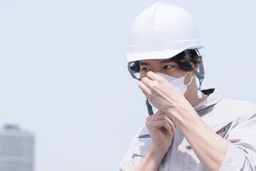 マスクをつける作業着姿の男性