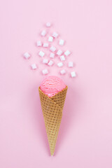 Strawberry ice cream in a cone with marshmallows on a pink background.