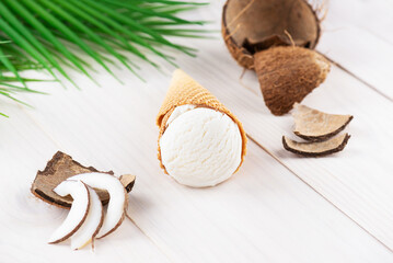 Coconut ice cream in a cone on a table with palm branches.