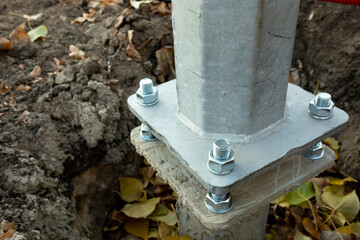 Metal pillar fastened to basement with anchor bolts and nuts. The support of the iron pillar.