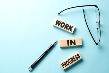 WORK IN PROGRESS text on a wooden block ,blue background