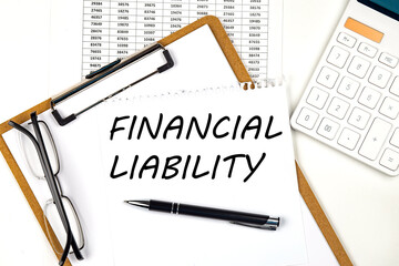 Text FINANCIAL LIABILITY on the white paper on clipboard with chart and calculator