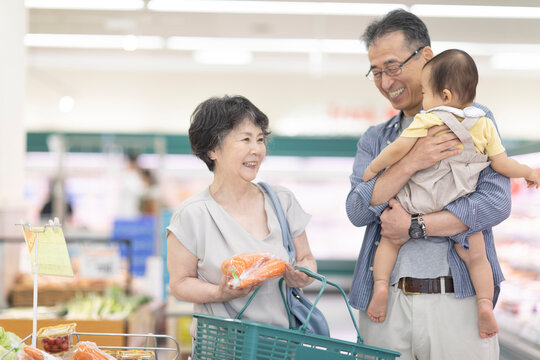 スーパーで買い物をするシニア夫婦と孫