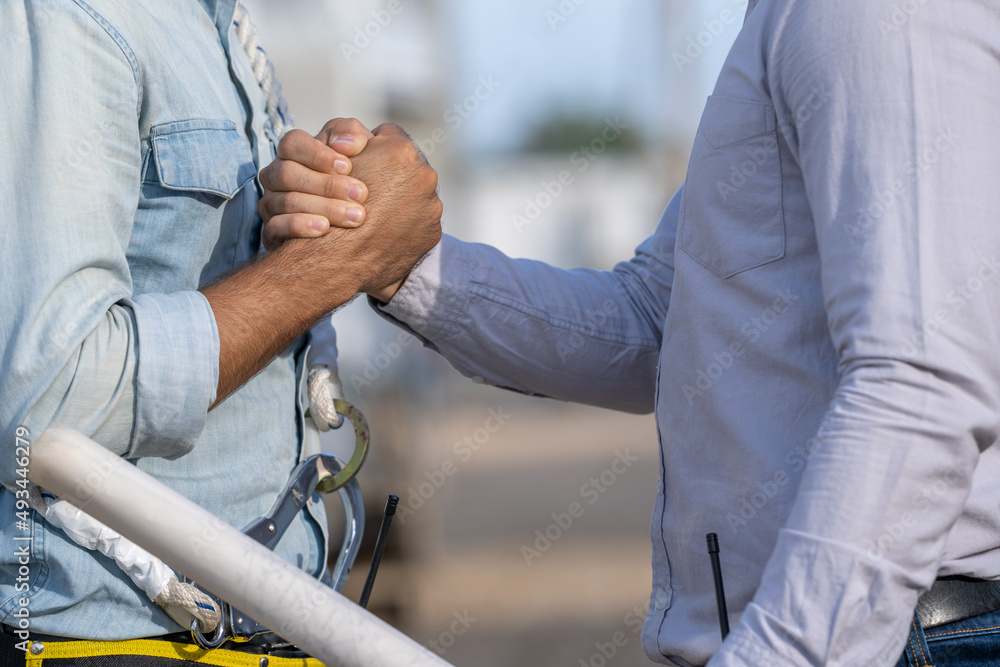Poster close up engineer and architect are shaking hands after finishing up meeting in construction site,co