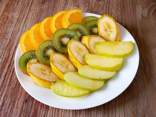 Bowl of healthy fresh fruit salad on wooden background.