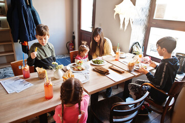 Mother with four kids spending time in cafe. Family lunch in the cafeteria.