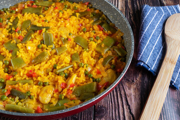 Rice paella with vegetables on a rustic background