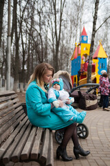 Stylish mom with   little baby   walking on   playground  in   spring