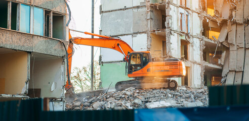 Process of demolition of  building. Excavator breaking old house.