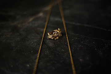 Gold ring in the shape of a crocodile with a gold chain on a dark marble background
