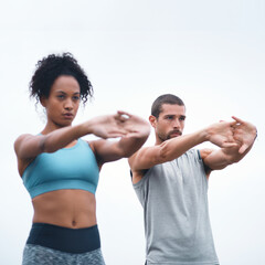 Loosening their joints before their run. Shot of two sporty young people stretching while...
