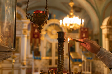 Orthodox Church. Christianity. Hand of priest lighting burning candles in traditional Orthodox...