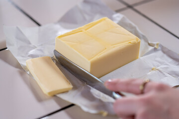 Cutting a slice of butter in a kitchen. Close-up.