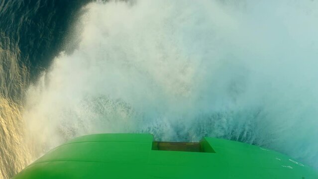 Storm. Wave breaks against side of ship. Lots of splashes. Top view. Green bow of vessel. Anchor