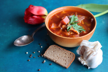 Still life food photo. Authentic Eastern European beet root soup. Bowl of red soup, sourdough bread, silver spoon, garlic and pepper top view photo. Healthy eating concept. 