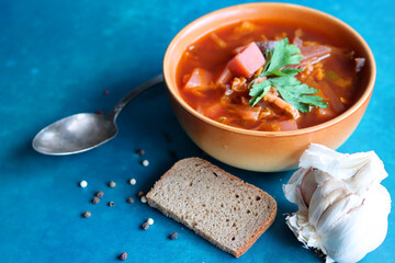 Still life food photo. Authentic Eastern European beet root soup. Bowl of red soup, sourdough bread, silver spoon, garlic and pepper top view photo. Healthy eating concept. 
