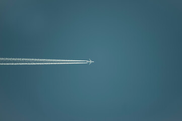 Airplane with white condensation tracks. Jet plane on clear blue sky with vapor trail.