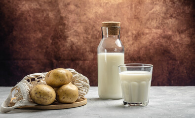 vegan potato milk in glass and raw potato. Alternative plant based milk. Healthy food trend. Healthy, clean eating. Vegan or gluten free diet. Long banner format. top view