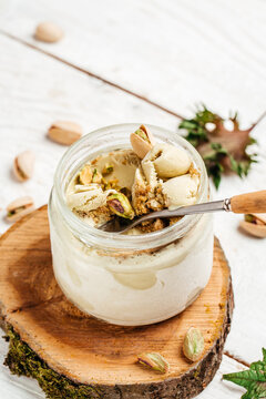 Homemade pistachio ice cream in a glass jar fresh pistachio over white background. vertical image. top view. place for text
